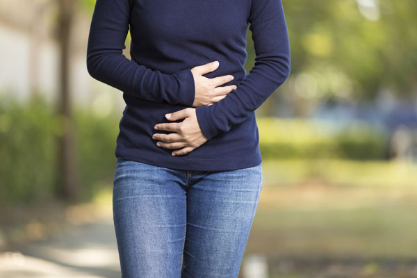 Woman walking down street holding on to her stomach