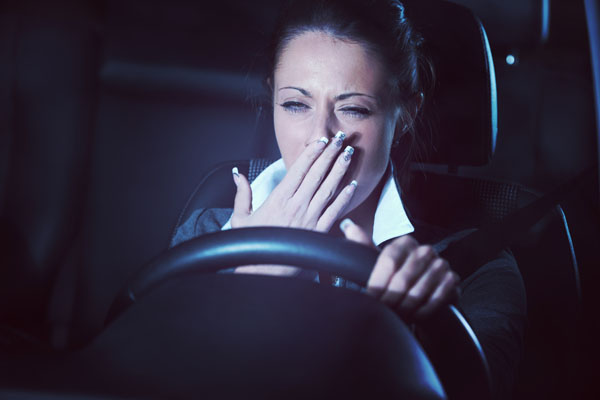Woman yawning while driving her car