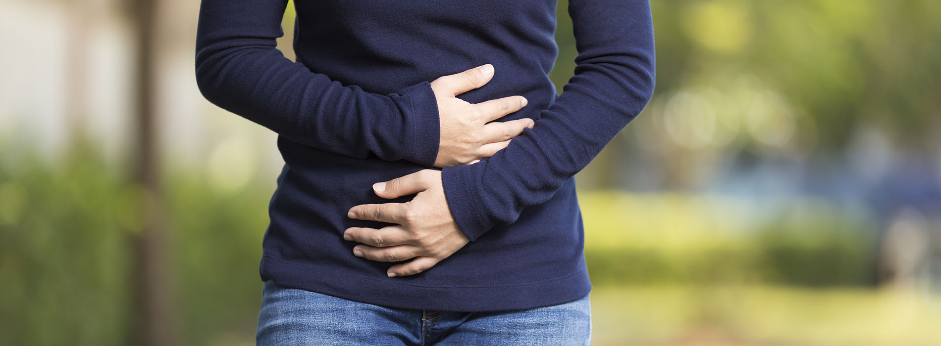 Woman walking down street holding her stomach