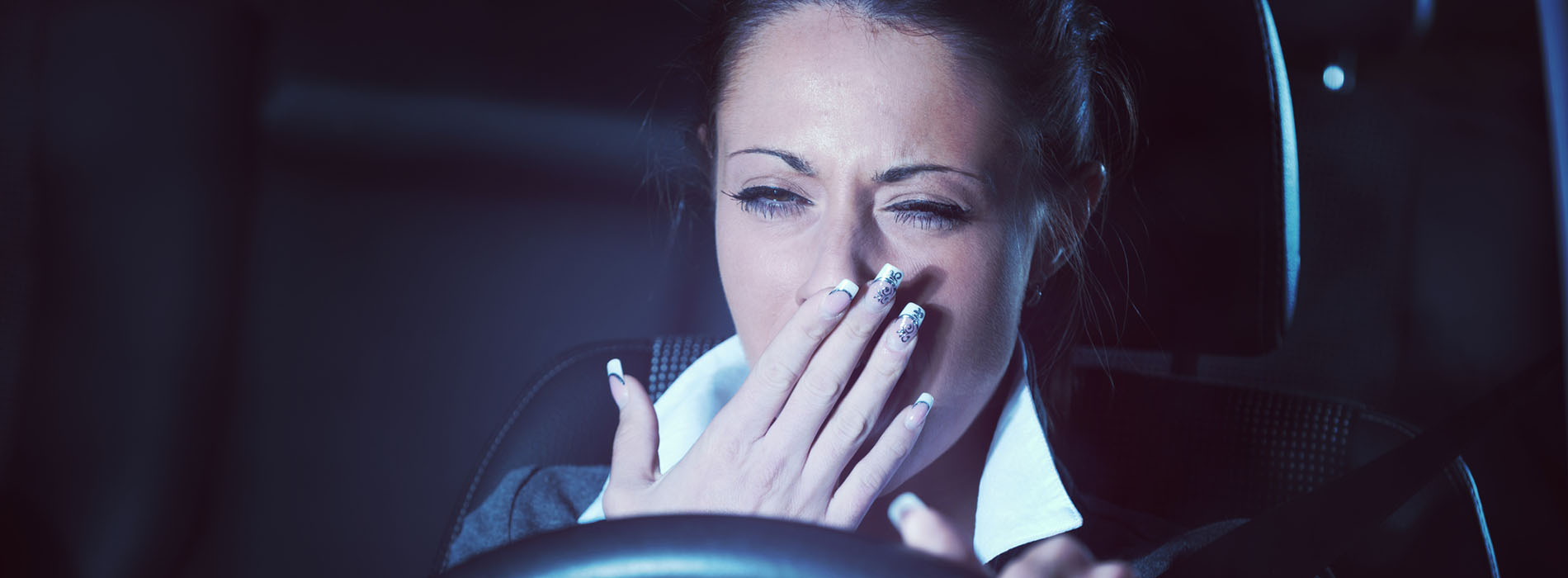Woman yawning while driving her car